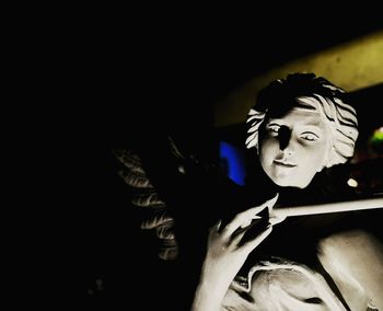 Close-up portrait of woman wearing hat against black background