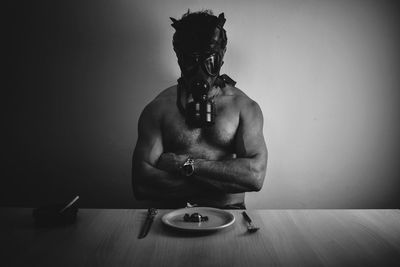 Young man wearing a teargas mask on table against wall