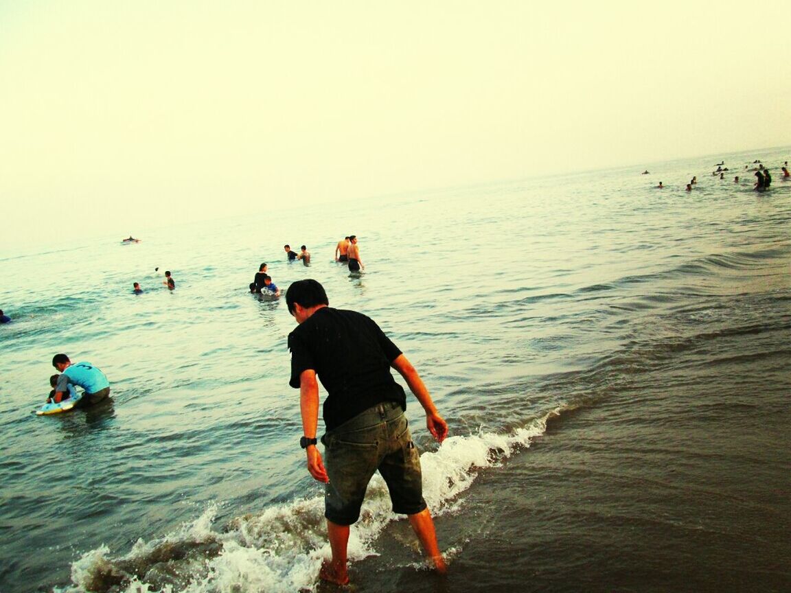 sea, water, leisure activity, lifestyles, beach, horizon over water, vacations, enjoyment, shore, wave, fun, full length, clear sky, men, waterfront, sand, boys, childhood, nature