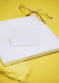 High angle view of eyeglasses on yellow background