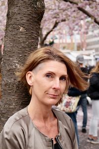 Portrait of smiling woman against tree trunk