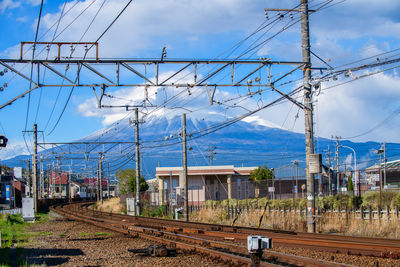 Railway tracks and power lines with mount fuji on a sunny day, japan