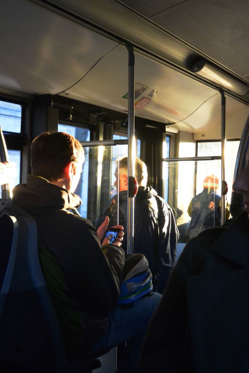 REAR VIEW OF MAN SITTING IN BUS