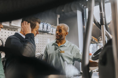 Salesman advising male customer in buying modern appliance at electronics store