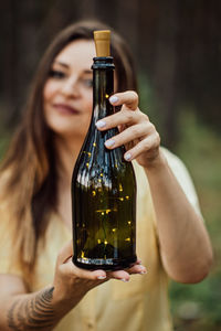 Enchantment, magic, midsummer ritual. woman with fern tattoo holding bottle with lights