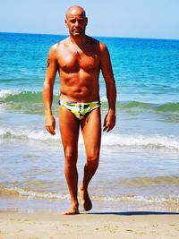 Full length of shirtless man standing on beach
