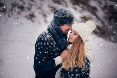 Romantic couple standing outdoors during snowfall