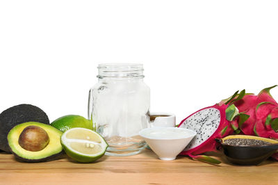 Close-up of fruits in glass jar on table against white background