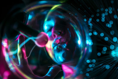 Digital composite image of woman and plasma ball with fiber optics