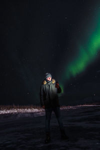 Full length of young man standing against illuminated star field at night