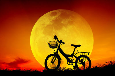 Silhouette bicycle against orange sky during sunset