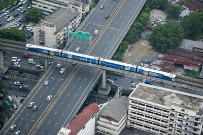 High angle view of train moving on bridge over elevated road in city