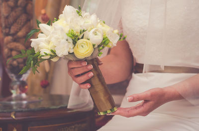 Midsection of bride holding rose bouquet