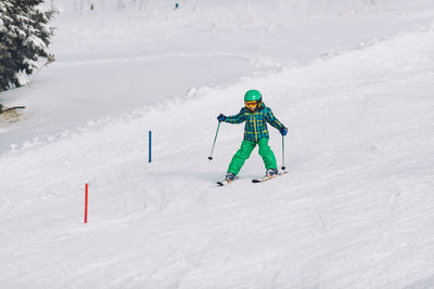 Full length of boy skiing on snow covered land