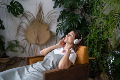 Relaxed woman in earphones rest after work in indoor greenhouse. stress relief and wellbeing concept