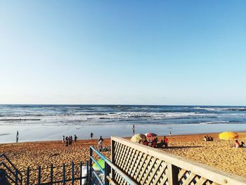 People on beach against clear sky