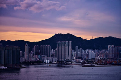 City by sea against sky at dusk