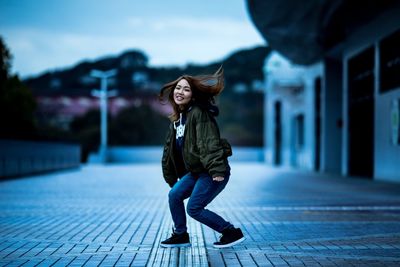 Full length of smiling young woman against sky