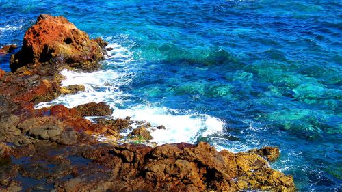 Rock formations by sea against blue sky