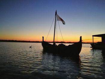 Silhouette sailboats in sea against clear sky during sunset