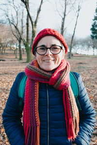 Portrait of young woman standing against trees
