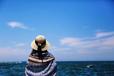 Rear view of woman wearing hat by sea against sky