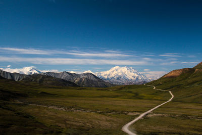 Scenic view of snowcapped mountains against blue sky