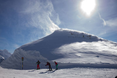 People skiing on snowcapped mountain against sky