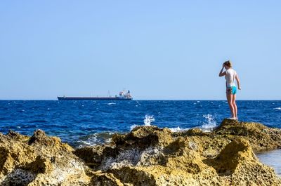 Woman standing on rock by sea