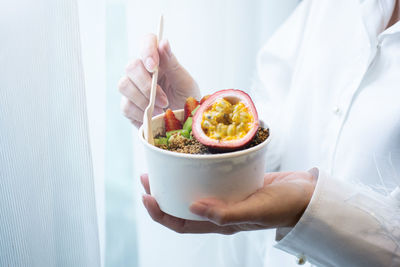 Midsection of person holding ice cream in bowl