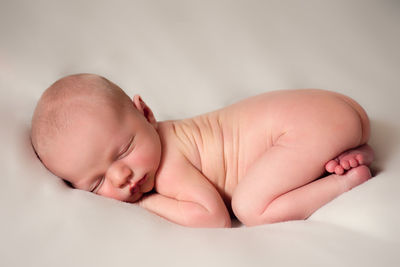 Newborn baby boy curled up sleeping