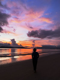 Rear view of silhouette man standing on beach during sunset