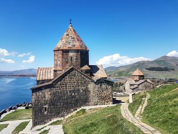 Historic building by sea against blue sky