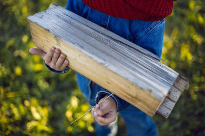 Child holds firewood in his hands in the village at his grandfather