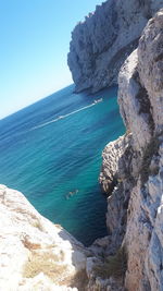 Rock formations by sea against blue sky