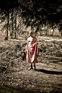 Woman with umbrella walking on field in forest