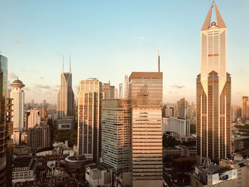 Orange sunset reflecting at modern buildings in asian cityscape against clear sky. office view.