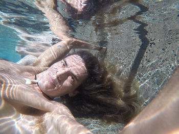 Long haired male submerged in pool