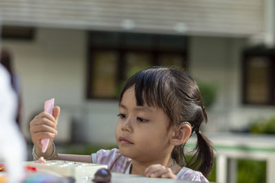 Close-up of cute girl playing with childs play clay at table outdoors