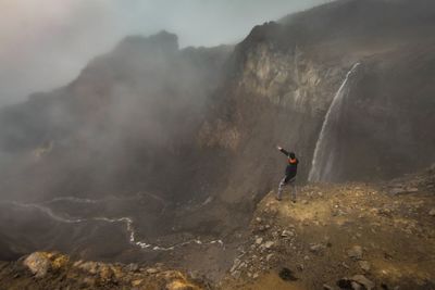 Man surfing on cliff against mountains