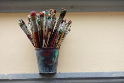 Close-up of multi colored pencils in pot on table against wall