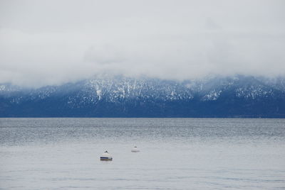 Scenic view of lake by snowcapped mountains against sky