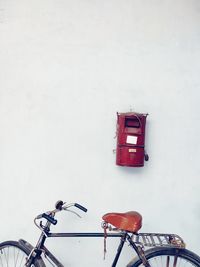 Bicycle parked against white wall