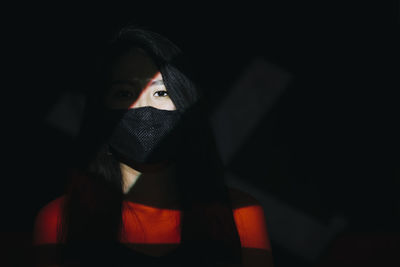 Portrait of woman covering face in darkroom