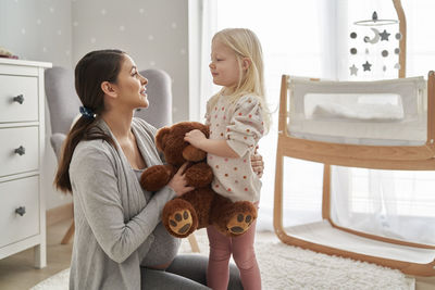 Smiling pregnant mother talking with daughter at home