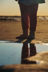 Low section of woman standing at beach