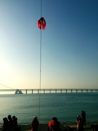 People on sea against clear sky