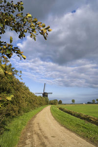 Road amidst field against sky