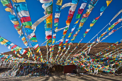 Low angle view of multi colored flags hanging against sky