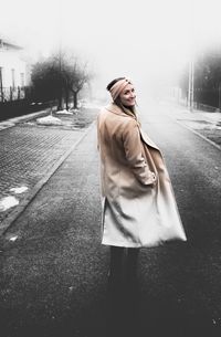 Portrait of smiling woman wearing jacket standing on street during winter